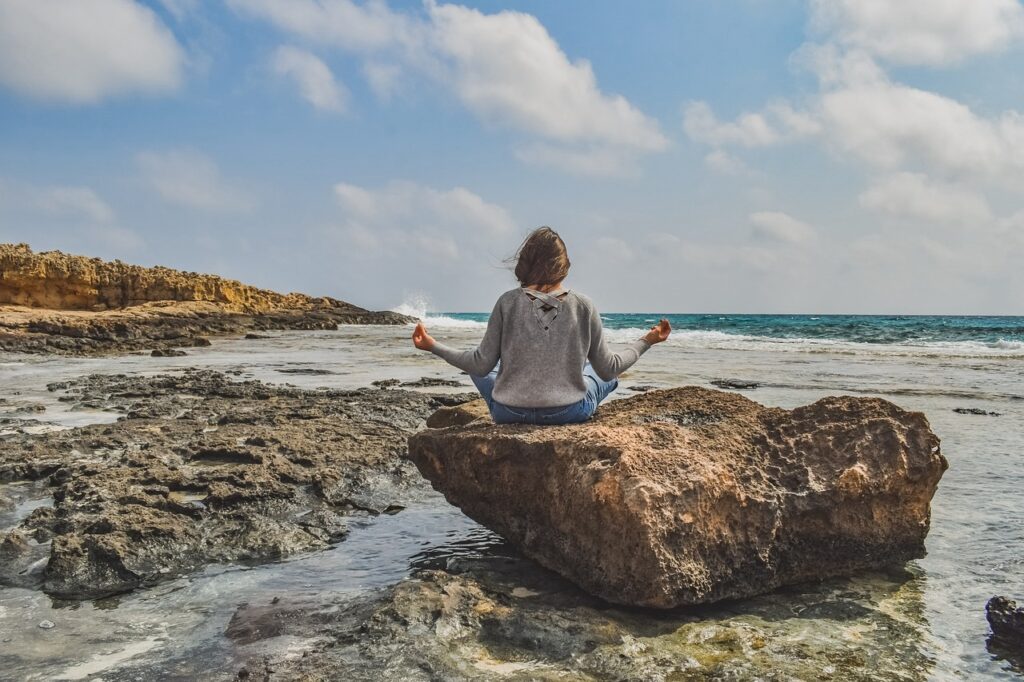 Una persona meditando al amanecer, en un entorno natural y sereno.